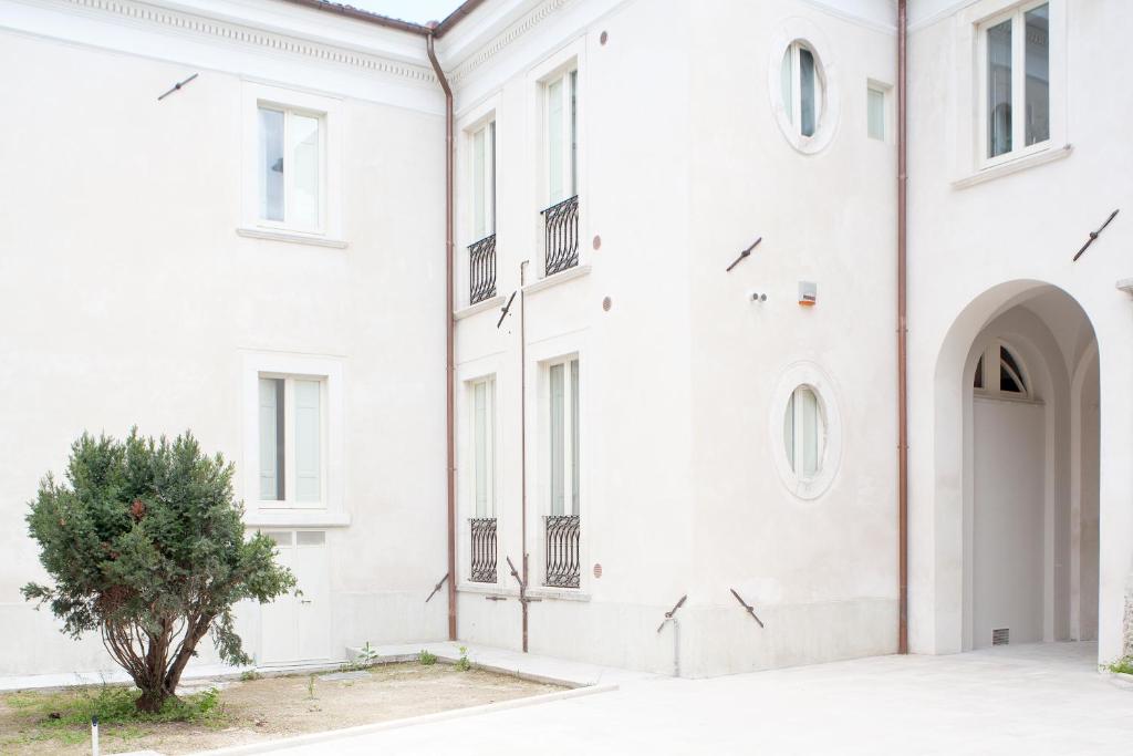a white building with a tree in front of it at Garibaldi Guest House in LʼAquila