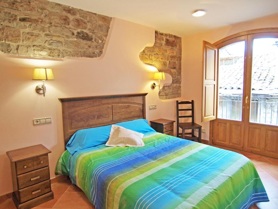 ein Schlafzimmer mit einem Bett mit einer farbenfrohen Tagesdecke in der Unterkunft Casa Fes Autural in Aínsa