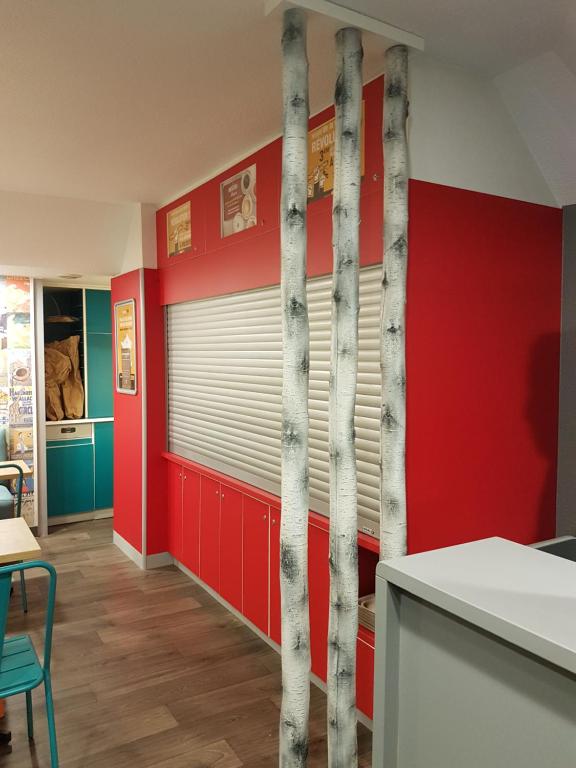 una cucina con pareti rosse e alberi di betulla sul muro di hotelF1 Lyon Saint Priest a Saint-Priest