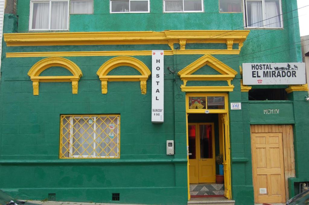 un edificio verde con ventanas amarillas y una puerta en Hostal El Mirador, en Punta Arenas