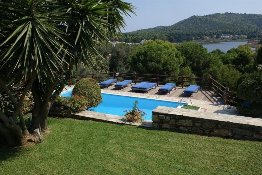 a pool with lounge chairs and a view of a lake at Villa Madag in Koukounaries