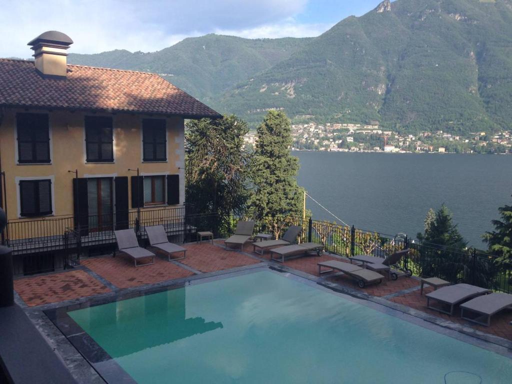 una piscina frente a un edificio con vistas al agua en Stylish JOIVY Flat with Garden, en Pognana Lario