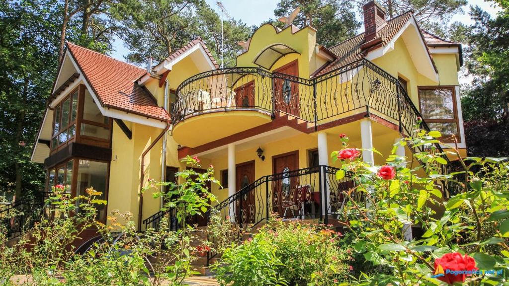 a large yellow house with a balcony at Willa Paweł in Pogorzelica