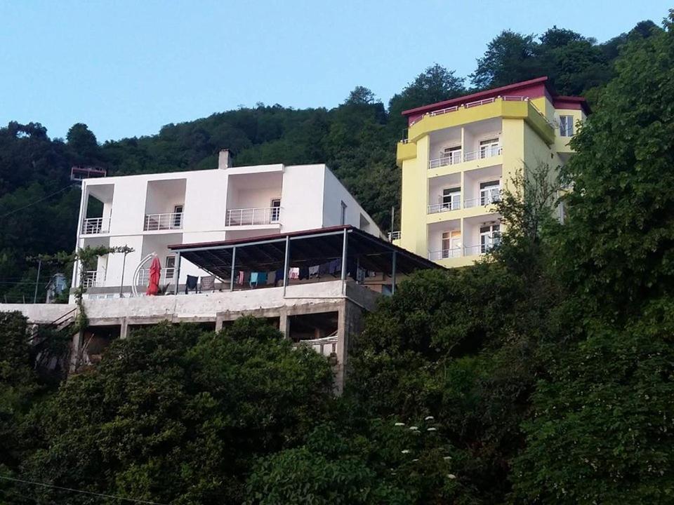 un edificio junto a una colina con árboles en Akhmed Guest House, en Kvariati