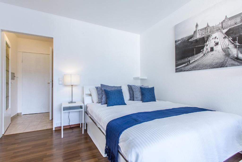 una camera bianca con letto e cuscini blu di Studio Lux city a Lussemburgo