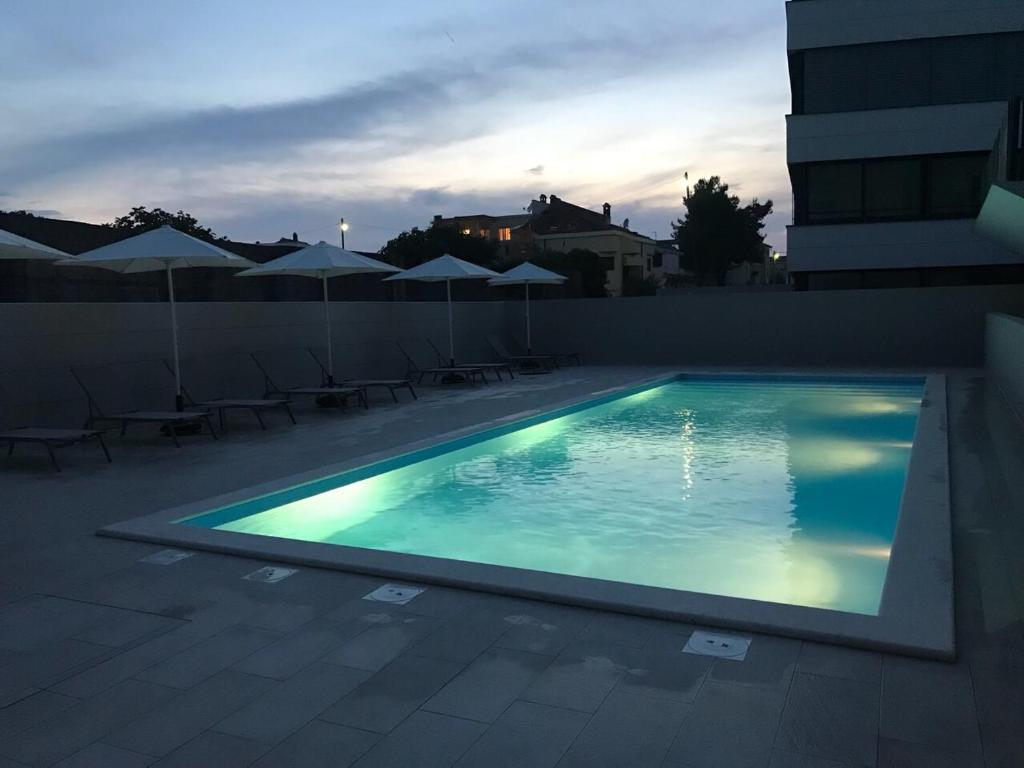 basen z leżakami i parasolami w budynku w obiekcie Luxury Apartment Kortina w mieście Zadar