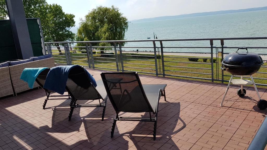 a patio with two chairs and a grill and the ocean at Apartment Balaton in Siófok