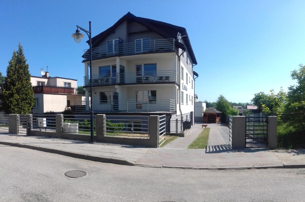 a white house with a black roof on a street at Stokrotka in Władysławowo