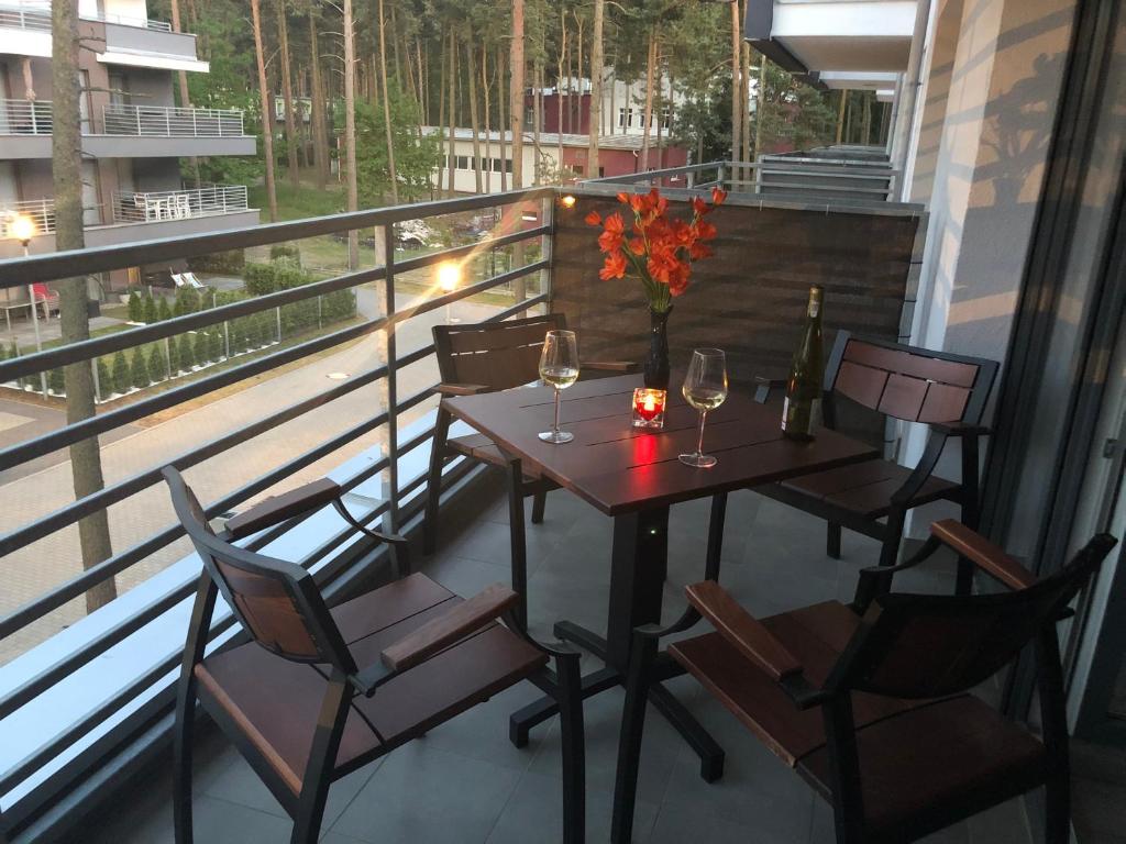 a table and chairs on a balcony with wine glasses at Apartament Jula 2 in Pogorzelica