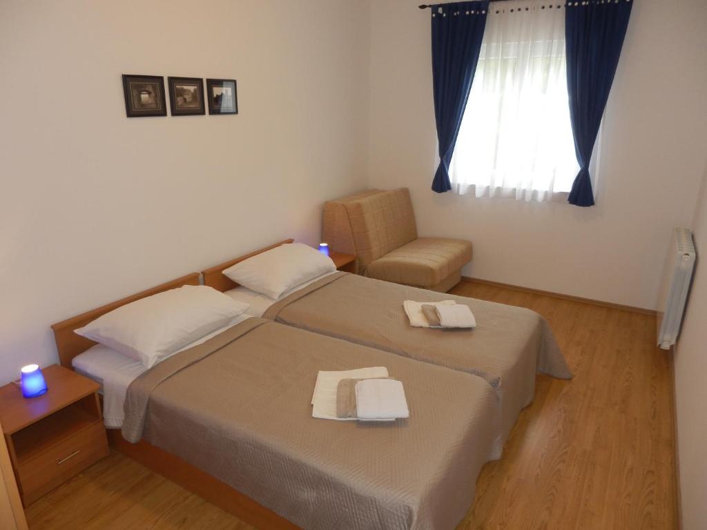 a bedroom with two beds and a chair and a window at Apartment Greta in Kanfanar