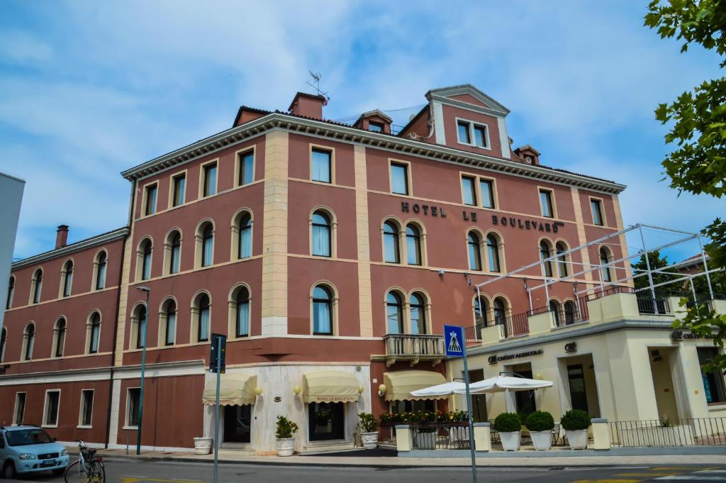 een groot gebouw van rode baksteen op de hoek van een straat bij Hotel Le Boulevard in Venetië-Lido