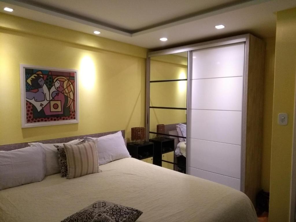 1 dormitorio con cama blanca y armario en Apê Balneário Camboriú Pé na Areia próximo a Roda gigante Com Churrasqueira, en Balneário Camboriú