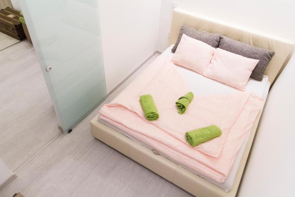 Una cama con sábanas rosas y toallas verdes. en Cozy Apartment Budapest, en Budapest