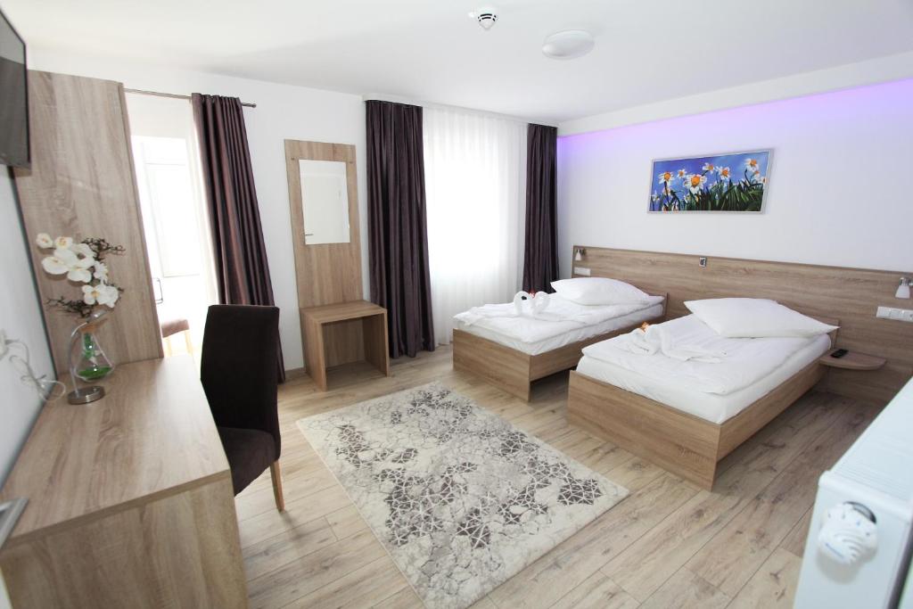pokój hotelowy z dwoma łóżkami i stołem w obiekcie Pension Villa Colosseo im Herzen von Meiningen w mieście Meiningen