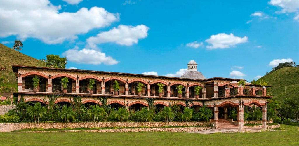a large brick building with a hill in the background at Hacienda San Vicente in Flores