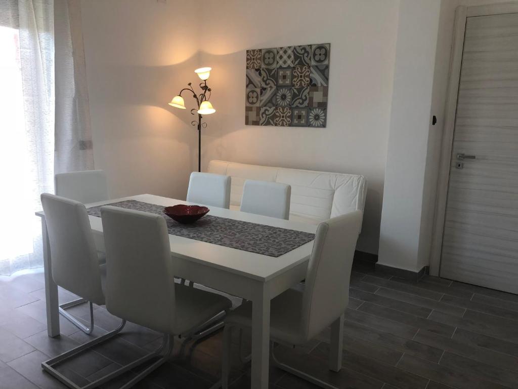 een eettafel met witte stoelen, een witte tafel en een stoeltje bij Solemar in Giardina Gallotti