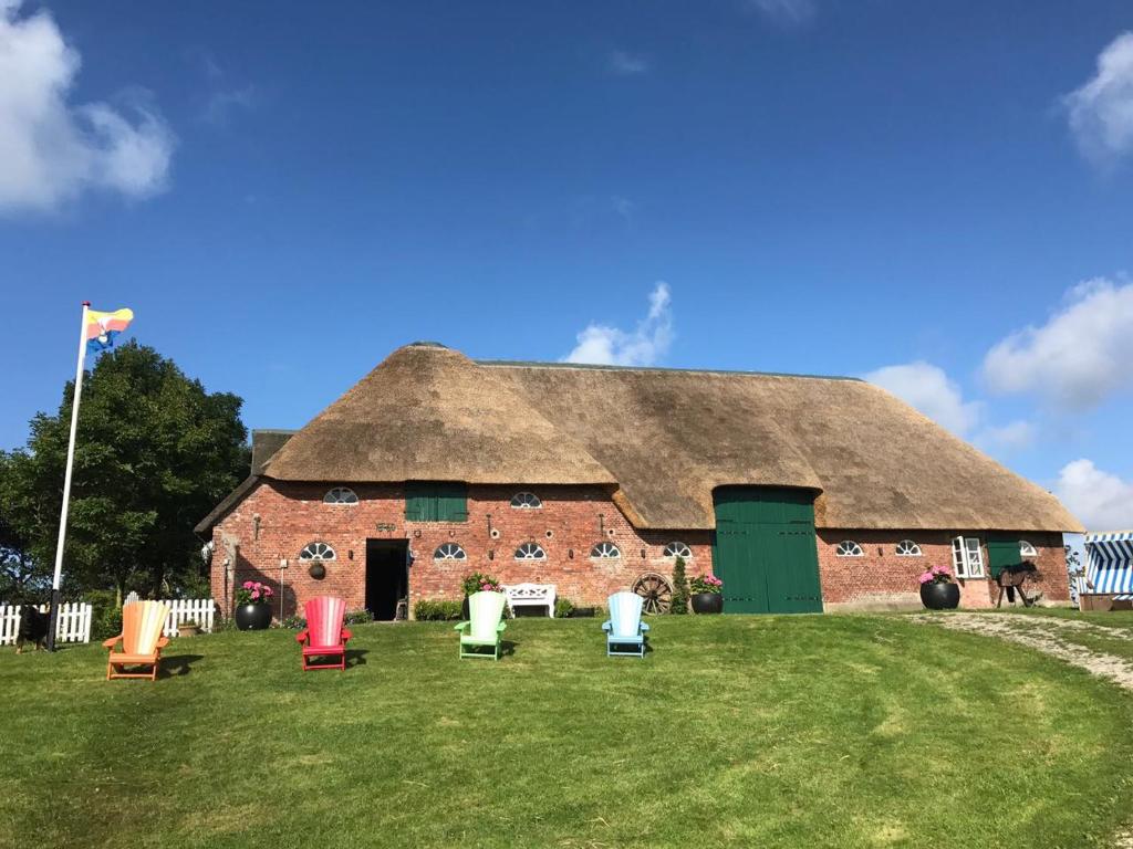 een groot bakstenen gebouw met stoelen ervoor bij Der historische Silberhof von 1856 in Pellworm