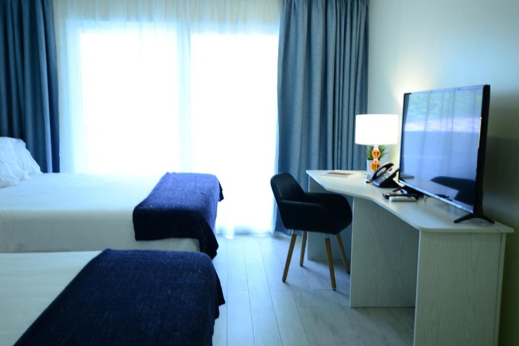 a hotel room with a bed and a desk with a computer at Quints Travelers Inn in Willemstad