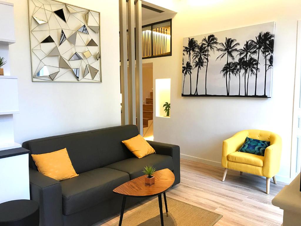 - un salon avec un canapé noir et un fauteuil jaune dans l'établissement Cannes, à Cannes