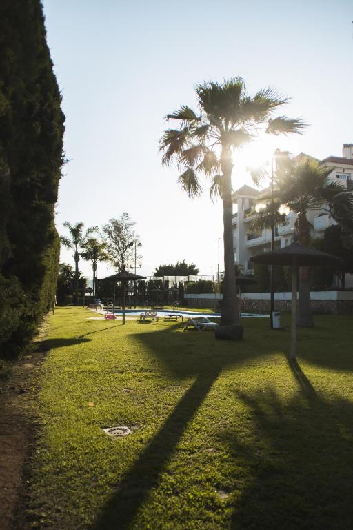 a park with two palm trees and a building at Cozy Apartment Banus in Marbella
