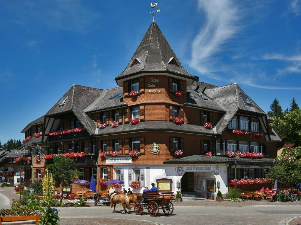 une calèche tirée par des chevaux devant un grand bâtiment dans l'établissement Hotel Schwarzwaldhof, à Hinterzarten