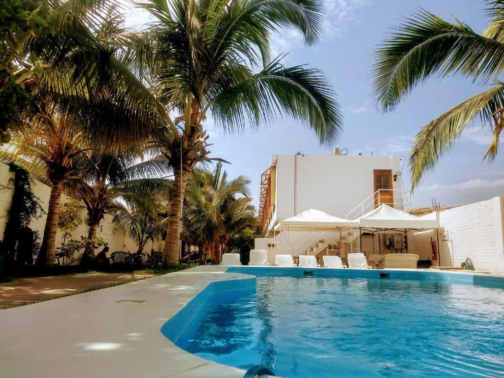 a swimming pool with palm trees and a building at Casavillamor in Máncora