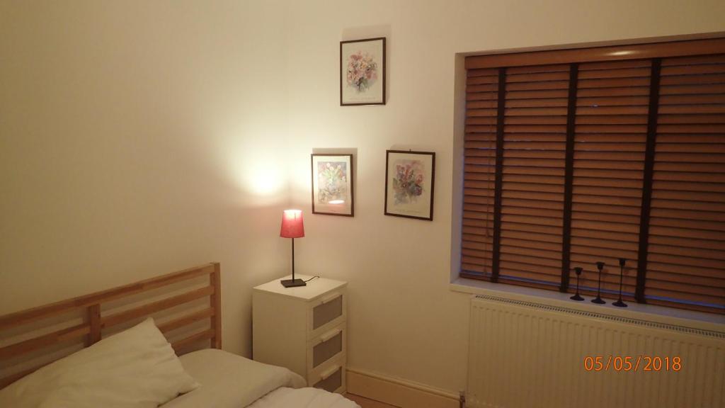 a bedroom with a bed and a red lamp on a night stand at Hill Apartments in London