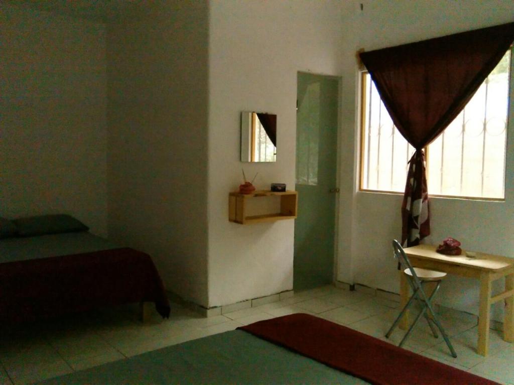 a bedroom with a bed and a table and a window at Posada Cielito Lindo in Mazunte