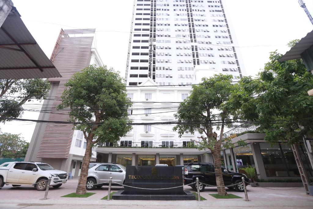 un edificio blanco alto con coches estacionados frente a él en Tecco Sky Hotel & Spa en Vinh