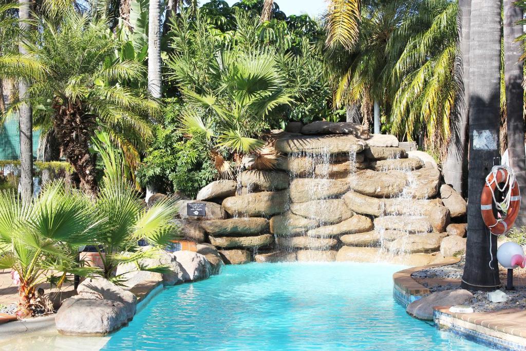 basen w ośrodku z wodospadem i palmami w obiekcie Swan Hill Resort w mieście Swan Hill