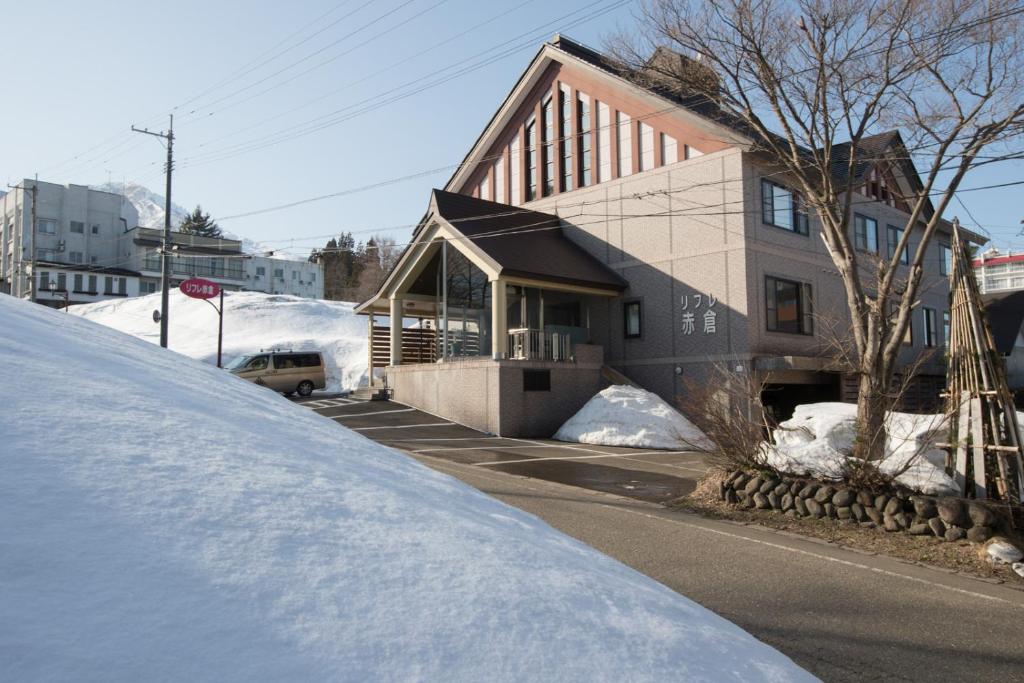 a house with snow on the side of a street at Refre Hotel in Myoko