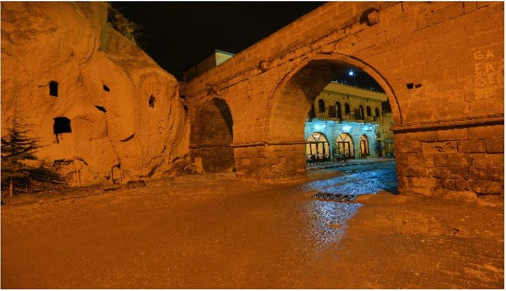 - un bâtiment en pierre avec une arche la nuit dans l'établissement Jerveni Cave Hotel, à Mustafapaşa