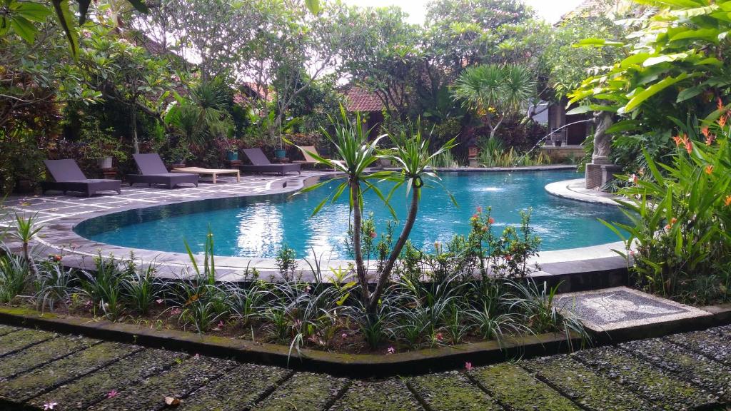 a swimming pool in a resort with chairs and plants at Arjana Bungalows 2 in Ubud