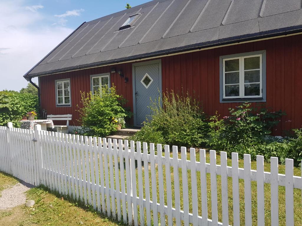 a red house with a white picket fence at Smultronbacken in Eljaröd