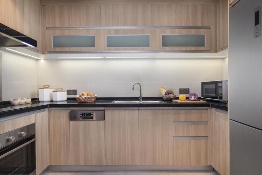 a kitchen with wooden cabinets and a sink at Somerset Harmony City Wuxi in Wuxi