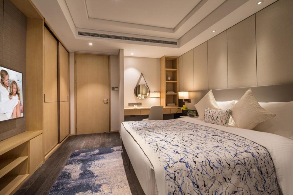 a hotel room with a bed and a flat screen tv at Somerset Harmony City Wuxi in Wuxi