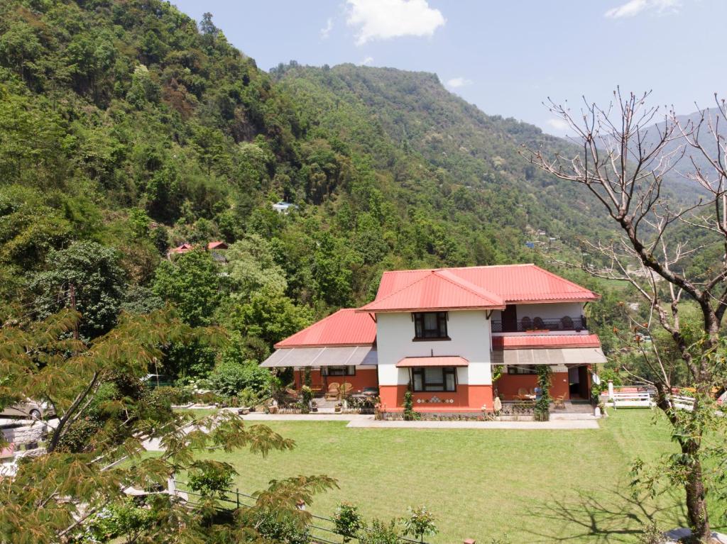 a house with a red roof in front of a mountain at Burpeepal in Gangtok