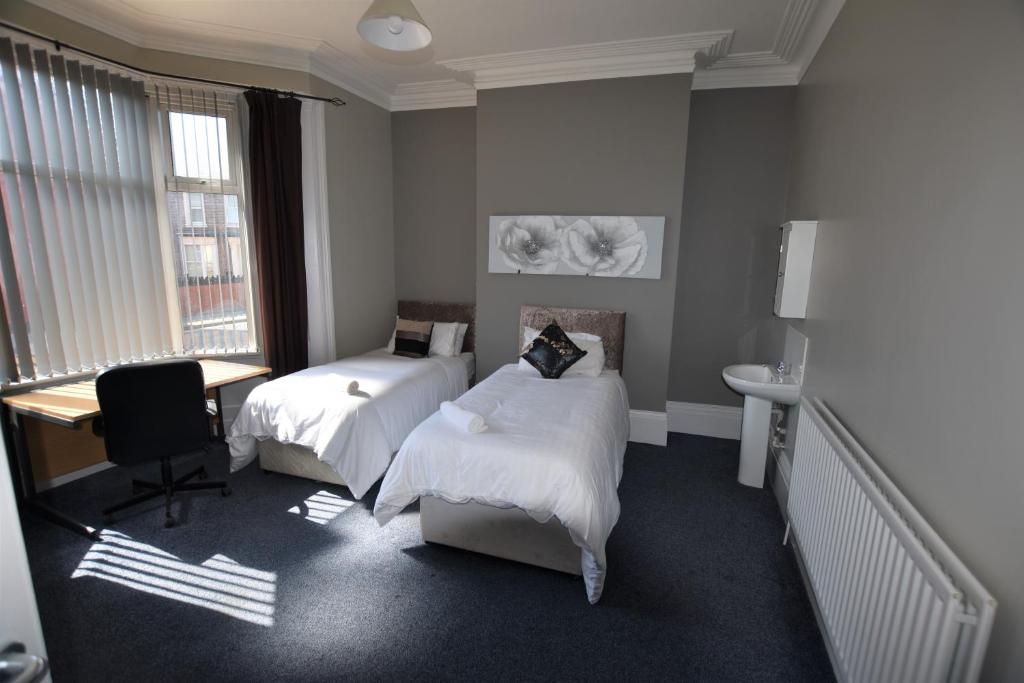 桑德蘭的住宿－Western Hill，一间卧室设有两张床、一张桌子和一个窗口。