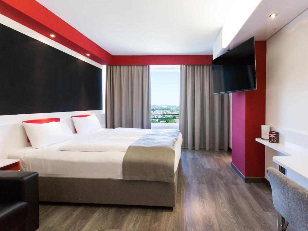 um quarto de hotel com uma cama e uma televisão de ecrã plano em DORMERO Hotel Stuttgart em Estugarda