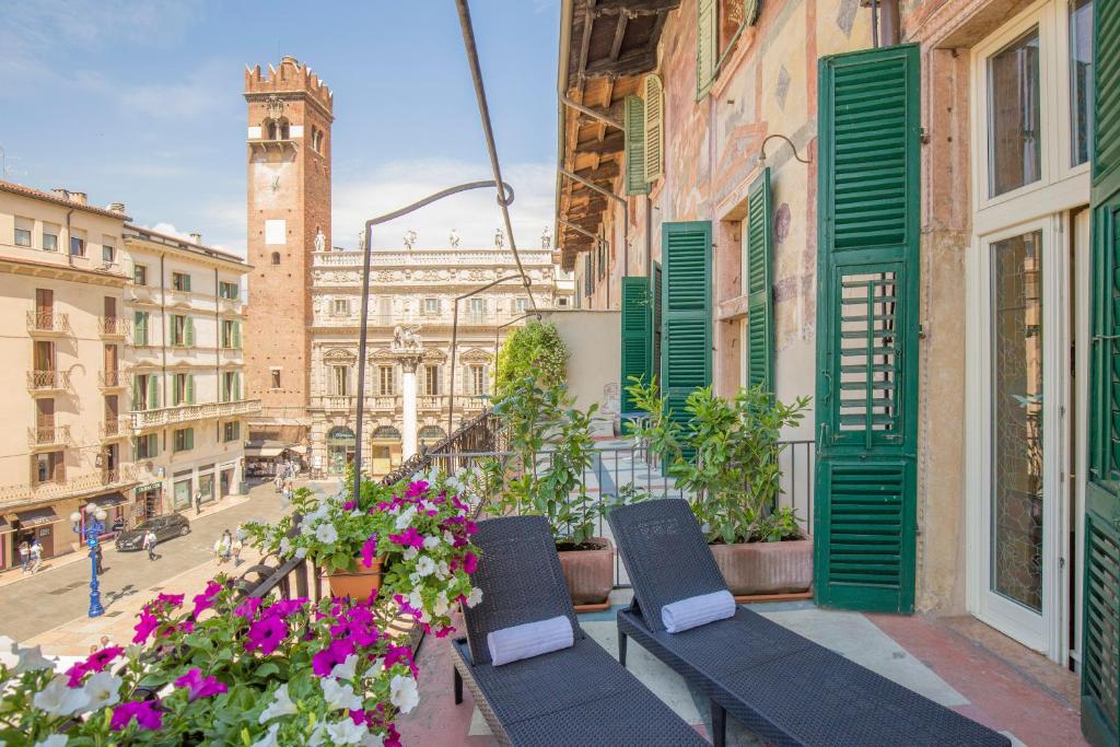 a balcony with two chairs and flowers on a city street at Corte Realdi Suites Piazza Erbe in Verona