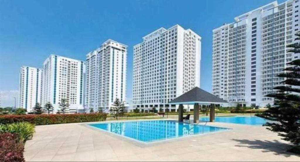 ein Schwimmbad vor einigen hohen Gebäuden in der Unterkunft Elizabeth 1830 @ Wind Residences in Tagaytay
