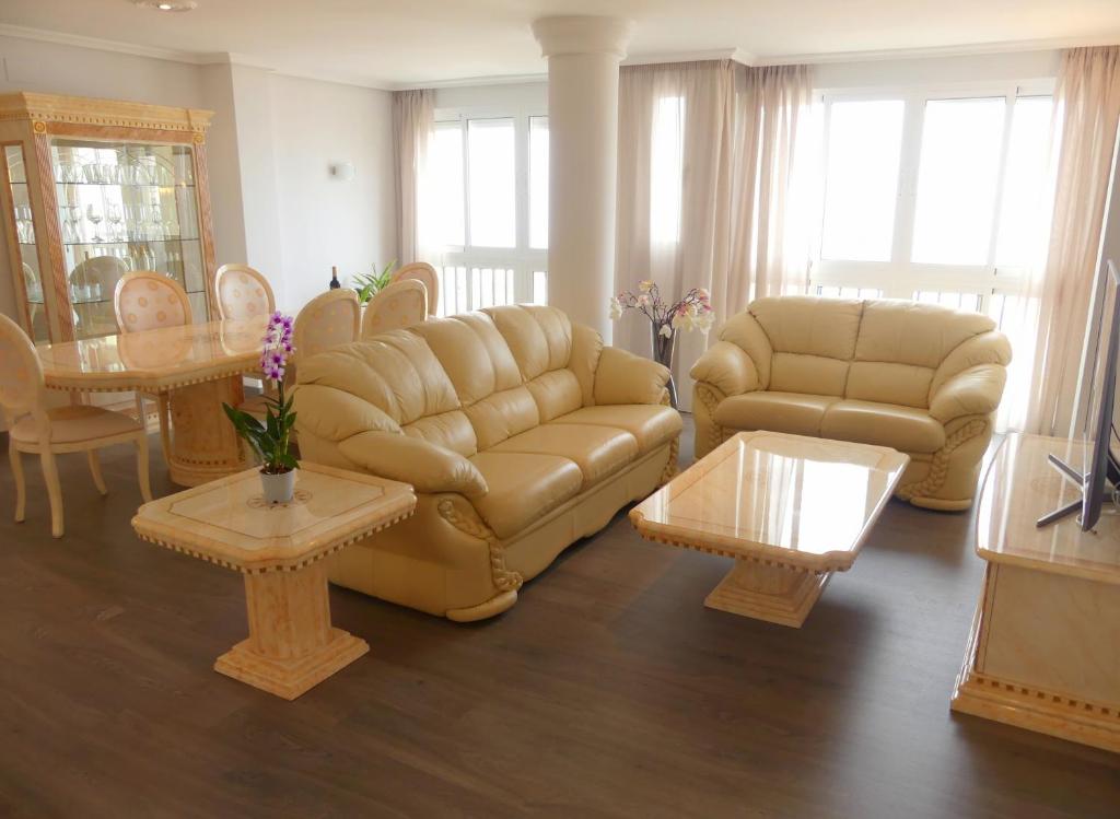 ein Wohnzimmer mit einem Sofa, einem Tisch und Stühlen in der Unterkunft DUPLEX LA CARIHUELA 1ª LINEA DE PLAYA APARTAMENTO COSTA DEL SOL in Torremolinos