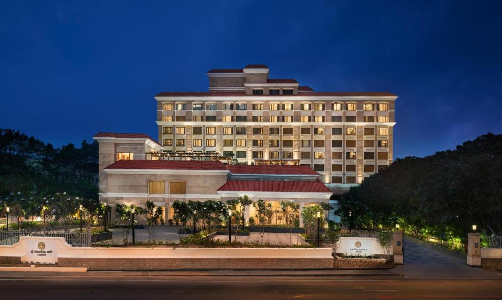 a large building with palm trees in front of it at The Residency Towers Coimbatore in Coimbatore