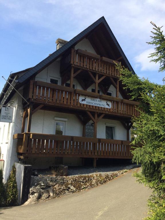 Cette grande maison en bois dispose d'un balcon sur le côté. dans l'établissement Pension Haus Am Hirschsprung, à Willingen