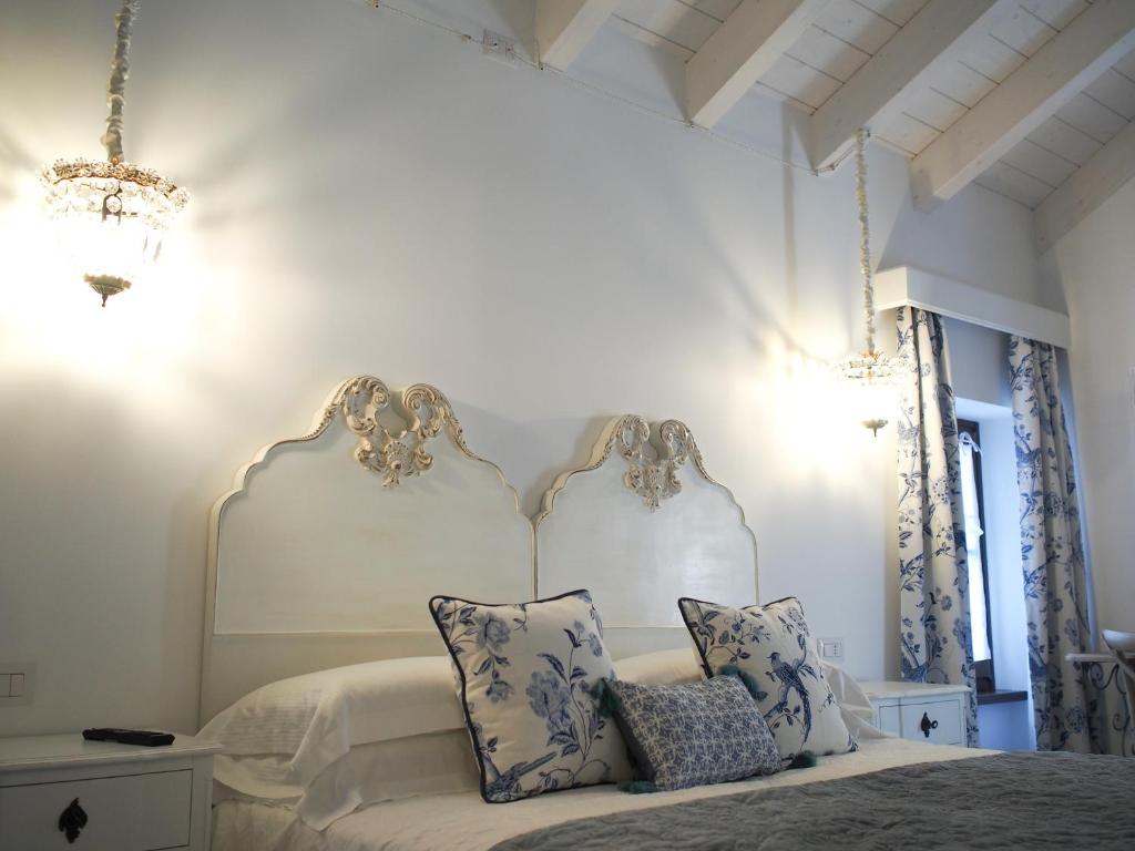 una camera da letto bianca con un letto con cuscini blu e bianchi di Le Sei Dame a Bardi