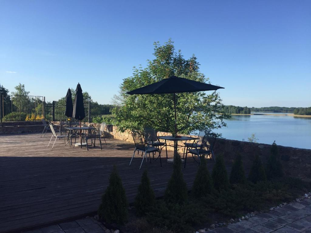een tafel en stoelen met een parasol naast een meer bij Villa Traku Terasa in Trakai