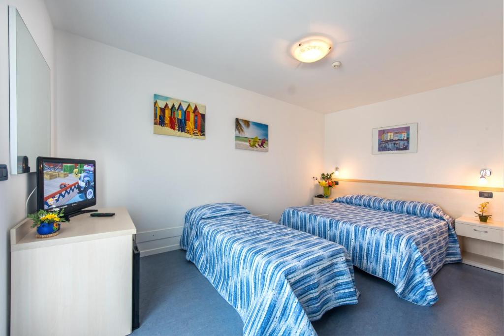 una camera d'albergo con due letti e una televisione di Hotel Minerva a Lignano Sabbiadoro