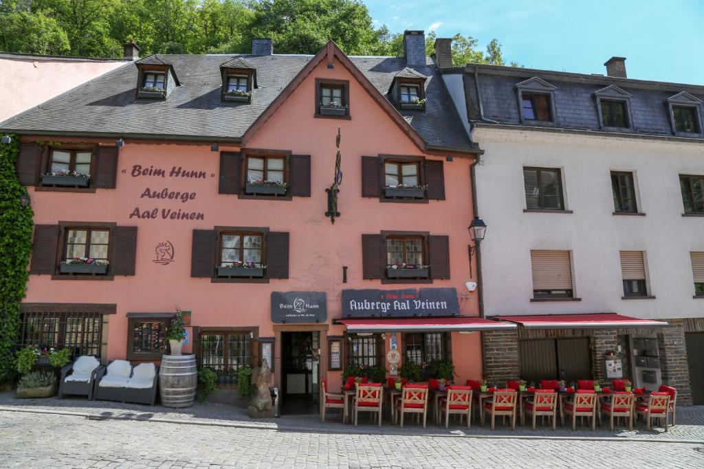 un bâtiment rose avec des tables et des chaises devant lui dans l'établissement Auberge Aal Veinen, à Vianden