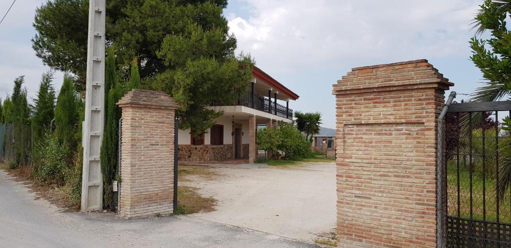 une clôture en briques et un portail en face d'une maison dans l'établissement Villa Manosalva, à Baena