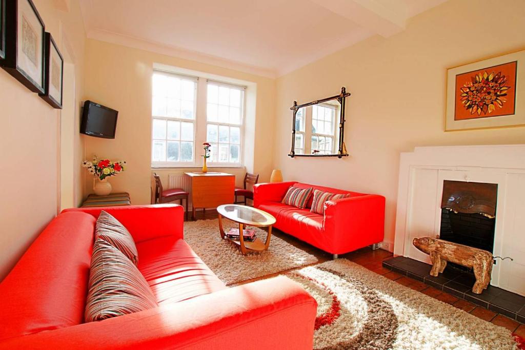 - un salon avec un canapé rouge et une cheminée dans l'établissement Bright and cosy 2BR Apt with workspace in New town, 5mins to Princes St, à Édimbourg